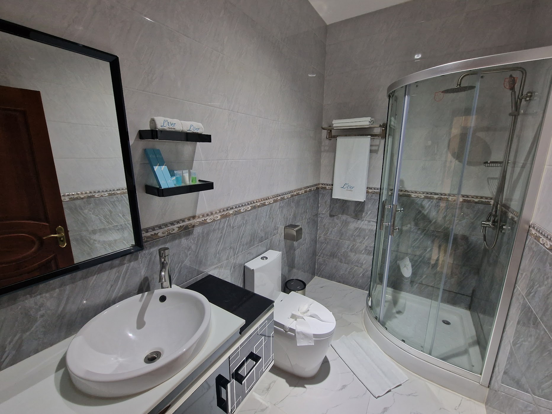 Marble-tiled en-suite bathroom with glass shower and branded amenities at L'ver Hotel, Somoto